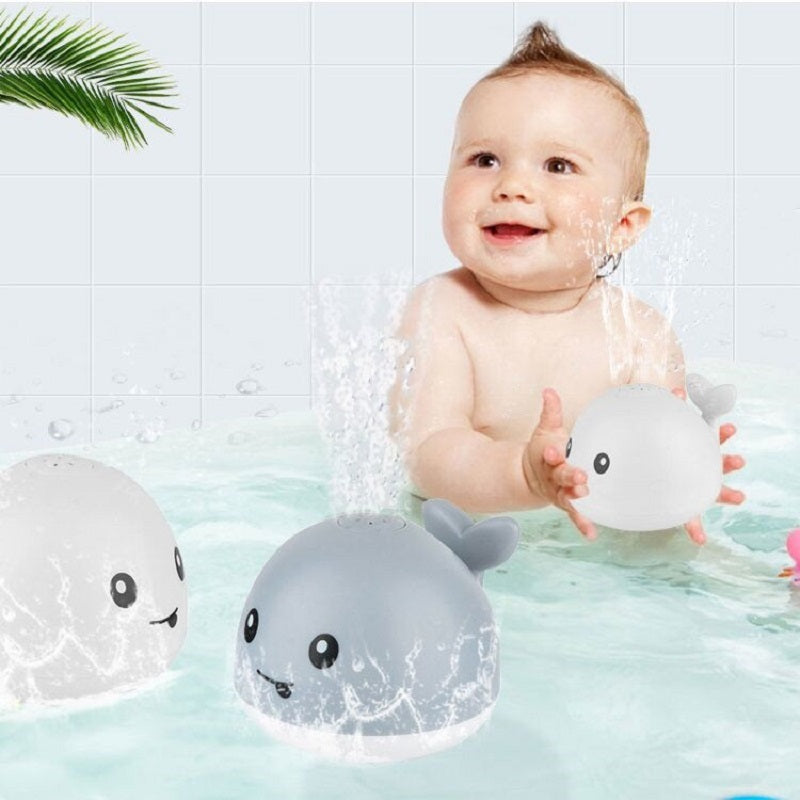 Baby playing with whale-shaped bath toys in a bathtub.