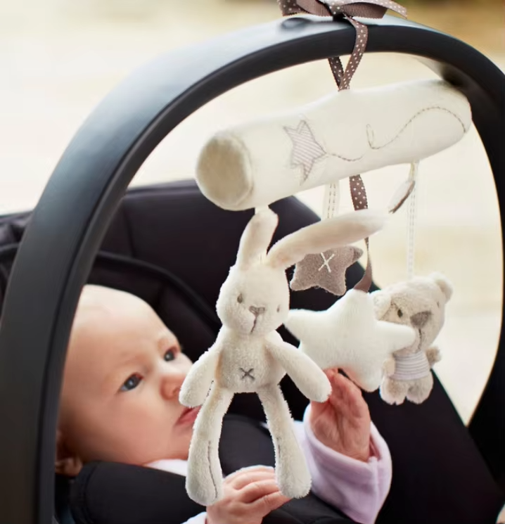 Baby in a car seat with a plush toy hanging from the car seat's handle