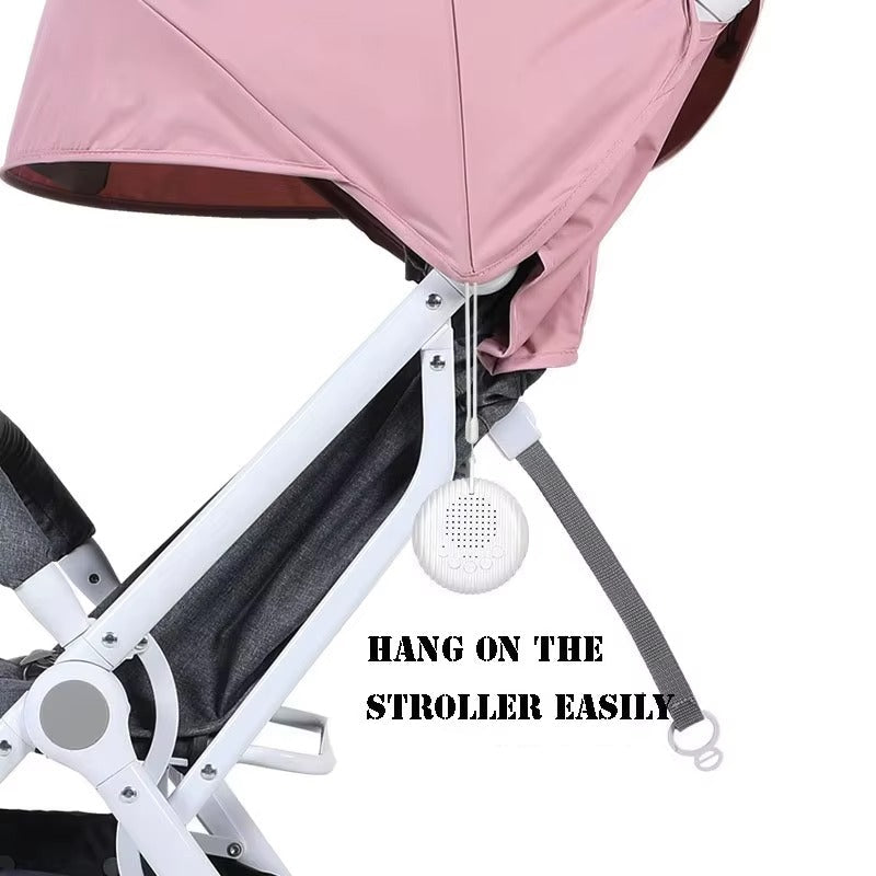 Baby stroller with a white noise machine hanging from it, on a white background.